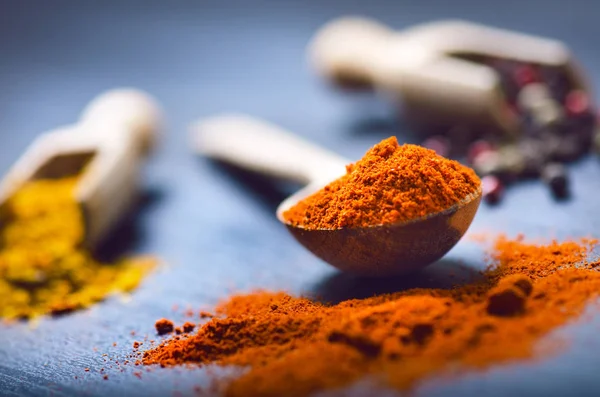 Colorful spices on a dark blue table. Vegetable. Concept of kitchen and cooking. Spicy on a wooden spoon. — Stock Photo, Image