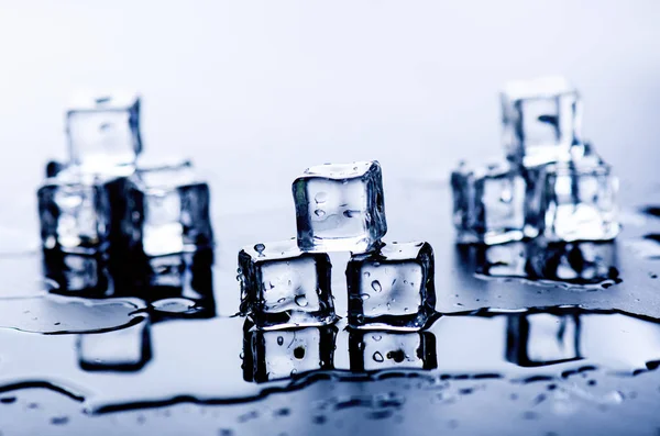 Iced isbitar som smälter på en blå tabell med reflektion. Vatten. Smältning av isen. — Stockfoto