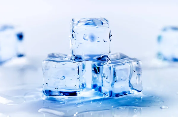 Iced isbitar som smälter på ett vitt bord med reflektion. Vatten. Smältning av isen. — Stockfoto