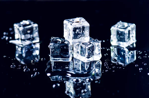 Iced isbitar som smälter på ett svart bord med reflektion. Vatten. Smältning av isen. — Stockfoto