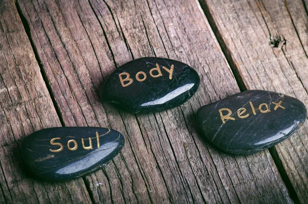 Ahşap bir masa üzerinde siyah taş tedavi. Spa ve sağlıklı yaşam konsepti. 