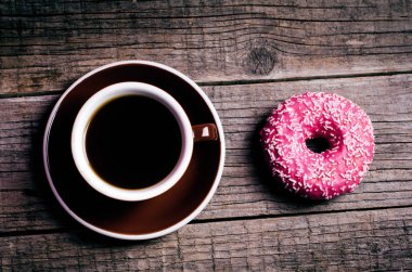 renkli donut ile ahşap bir masa üzerinde sprinkles. Retro tarzı. Bir fincan kahve. Çörek iki tür. Pasta ve tatlı. Gıda ayrıntı. Yakın çekim. Pastel renk 