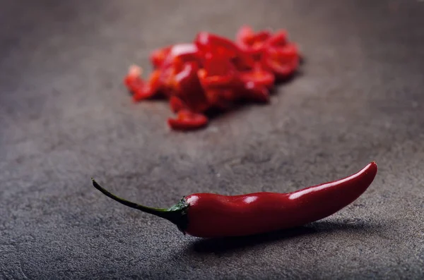 Nakrájené červené chilli papričky na černém pozadí. Pikantní na dřevěnou lžící. Zelenina. Koncept teplé jídlo. — Stock fotografie