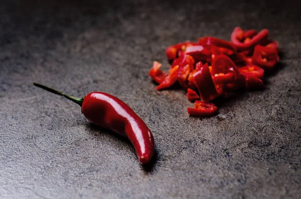 Peperoncino rosso tagliato su fondo nero. Speziato su un cucchiaio di legno. Verdura. Concetto di cibo caldo . — Foto Stock