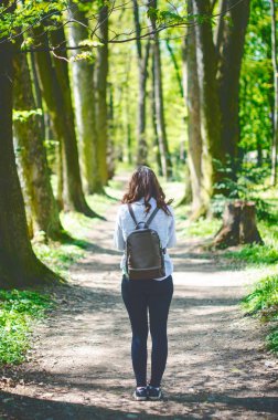 Genç kadın bir yolu ormandaki bir fotoğraf al. Güzel kadın çantası. Doğa. Yaprak döken ağaçlar. Bahar zamanı. Zevk hava ve güneş ışığı