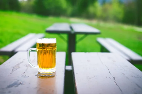 Copo de cerveja leve com espuma em uma mesa de madeira. Festa de jardim. Fundo natural. Álcool. Projecto de cerveja . Fotos De Bancos De Imagens