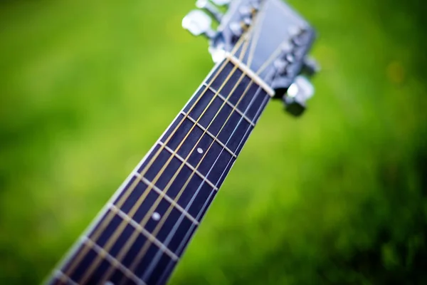 Detalle de guitarra acústica en una hierba. Fondo natural con flores, hierba y sol. Instrumento musical . —  Fotos de Stock