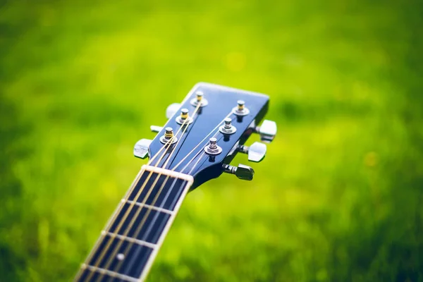 Detalle de guitarra acústica en una hierba. Fondo natural con flores, hierba y sol. Instrumento musical . —  Fotos de Stock