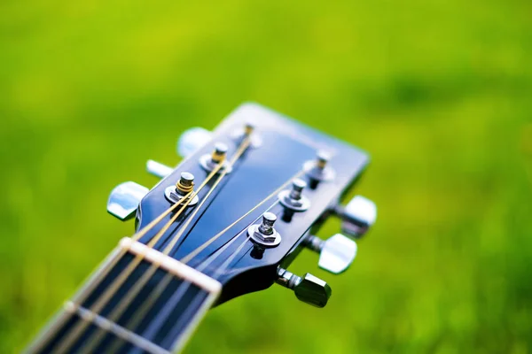 Detalle de guitarra acústica en una hierba. Fondo natural con flores, hierba y sol. Instrumento musical . —  Fotos de Stock