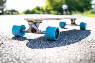 Güneşli havalarda yolda longboard. Kaykay etrafında insanlar. Yolu bir parkta. Kentsel sahne.