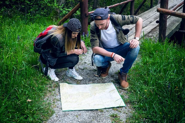 Young couple using a map on a adventure trip. Trip in a nature. Young happy people showing on a map. Traveler lifestyle