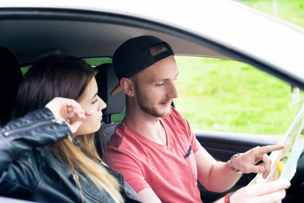 Feliz pareja joven, amigos sentados en el coche y mirando el mapa. Hora de verano. Gente caucásica. Concepto de transporte . — Foto de Stock