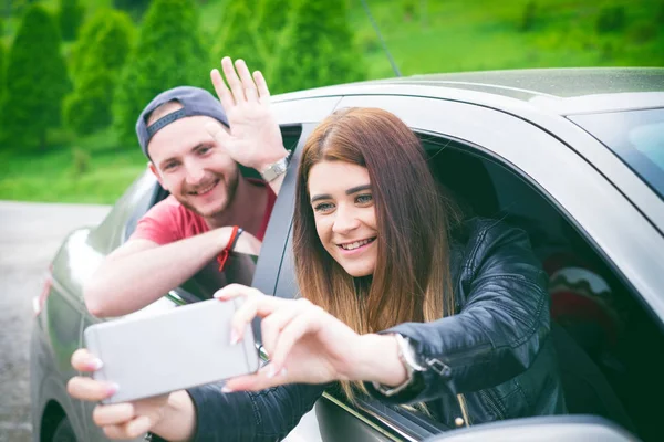 Feliz pareja joven, amigos haciendo selfie mientras están sentados en el coche. Hora de verano. Gente caucásica. Concepto de transporte . — Foto de Stock