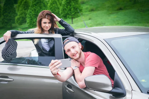 Feliz pareja joven, amigos haciendo selfie mientras están sentados en el coche. Hora de verano. Gente caucásica. Concepto de transporte . — Foto de Stock