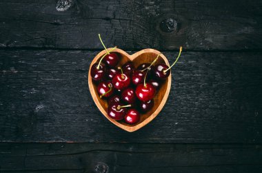 Siyah bir masada kirazlar doğal ahşap bir masa. Taze gıda konsepti. Meyve. Yaz zamanı.