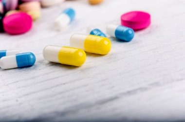 Ahşap kaşık tablet dolu. Beyaz bir masada eczane geçmişi. Beyaz arka planda tabletler. Haplar. İlaç ve sağlıklı. Kapsülleri kapatın. Farklı çeşit haplar.