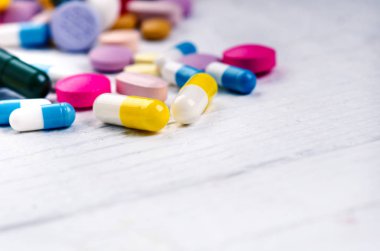 Ahşap kaşık tablet dolu. Beyaz bir masada eczane geçmişi. Beyaz arka planda tabletler. Haplar. İlaç ve sağlıklı. Kapsülleri kapatın. Farklı çeşit haplar.