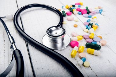 Beyaz bir masada eczane geçmişi. Beyaz ahşap arka planda steteskop. Bir metin için boşluk kopyala. Beyaz arka planda tabletler. Haplar. İlaç ve sağlıklı.. 