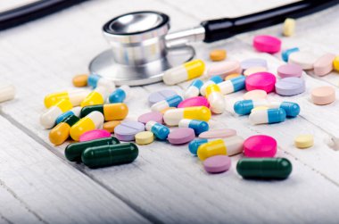 Beyaz bir masada eczane geçmişi. Beyaz ahşap arka planda steteskop. Bir metin için boşluk kopyala. Beyaz arka planda tabletler. Haplar. İlaç ve sağlıklı.. 