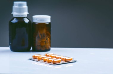 Beyaz arka planda izole edilmiş bir sürü tablet. Bardaktaki hapların yansıması. İlaç geçmişi var. Eczane. Kapsülleri kapatın. İlaçlar, cam şişedeki takviyeler..