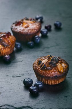 Taze, çilekli yabanmersinli kekler, tahta tahtada çikolata ve şeker ve meyveli taş arka plan. Yemek arkaplanı. Hamur işi kavramı. 