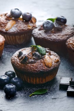 Taze, çilekli yabanmersinli kekler, tahta tahtada çikolata ve şeker ve meyveli taş arka plan. Yemek arkaplanı. Hamur işi kavramı. 