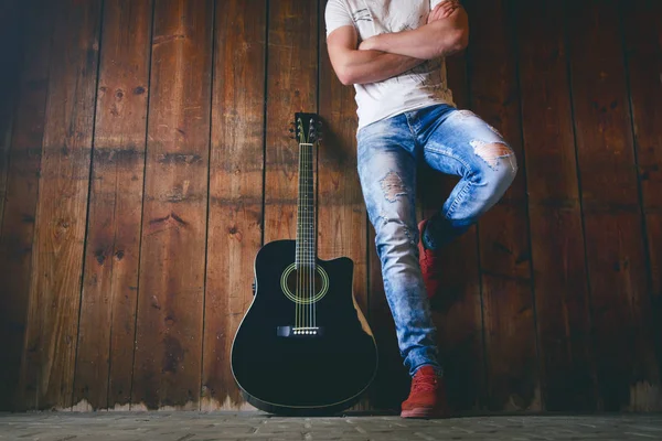 Metin ve gitarist için kopyalama alanı olan ahşap bir dokuda akustik gitar. Müzik ve eğlence konsepti. Gitar ahşap duvara dayanıyor.. 