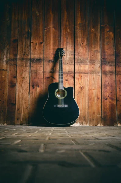 Metin ve gitarist için kopyalama alanı olan ahşap bir dokuda akustik gitar. Müzik ve eğlence konsepti. Gitar ahşap duvara dayanıyor.. 