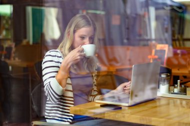 Young woman drinking coffee inside a cafeteria