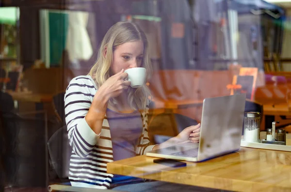 Young woman drinking coffee inside a cafeteria
