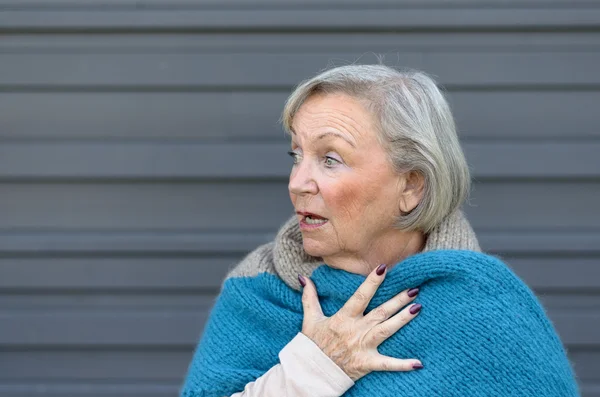 Startled elderly woman clasping her chest — Stock Photo, Image