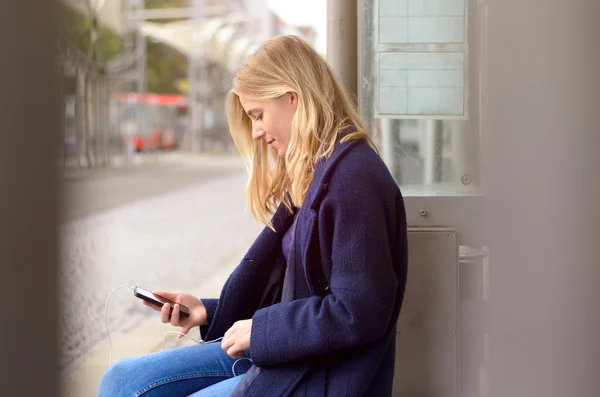 Oturan bir genç bayan bir otobüs beklerken — Stok fotoğraf