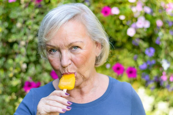 Elderly woman enjoying a refreshing iced lolly — Stock Photo, Image