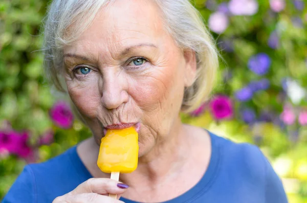 Elderly woman enjoying a refreshing iced lolly — Stock Photo, Image