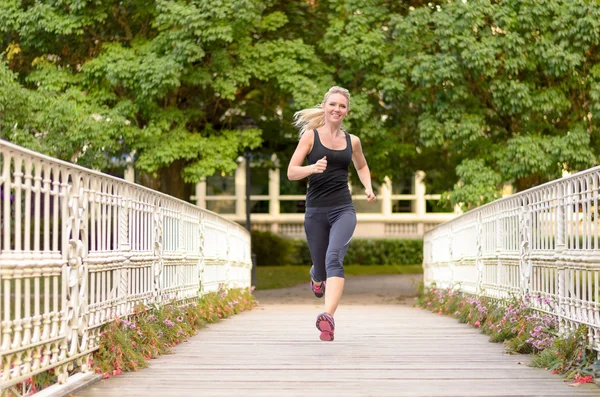 Fit active woman running across a bridge