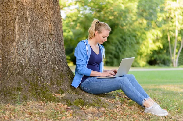 노트북을 사용 하 여 공원에서 편안한 젊은 여자 — 스톡 사진