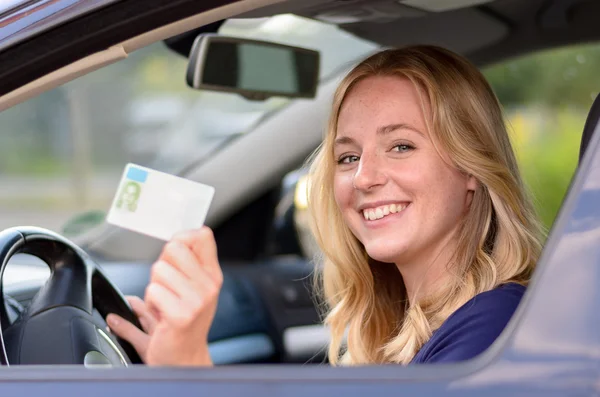 Щаслива молода жінка, що показує водійські права — стокове фото