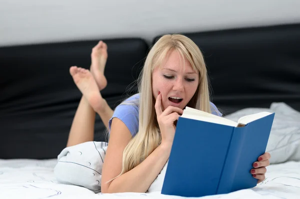 Mujer leyendo un libro mientras se relaja en su cama — Foto de Stock