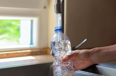 Woman filling a plastic bottle with water