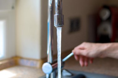 Woman turning on a tap with running water
