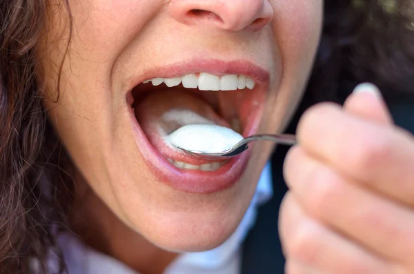 Mulher tomando uma boca cheia de creme ou sorvete — Fotografia de Stock