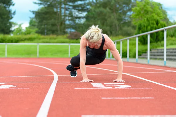 Athletic woman warming up hip muscles at track