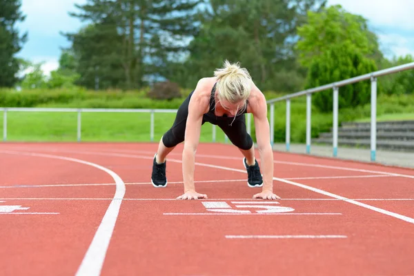 Single woman stretching calf muscles at race track