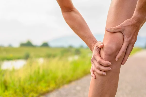 Mujer sosteniendo su rodilla lesionada — Foto de Stock