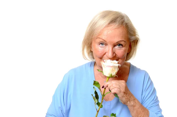 Elderly woman smelling a fresh pink rose — Stock Photo, Image