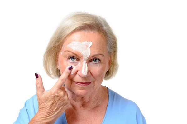 Attractive blond senior lady applying cosmetics — Stock Photo, Image