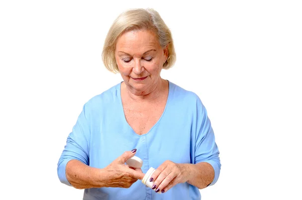 Пожилая женщина берет косметический крем из банки — стоковое фото