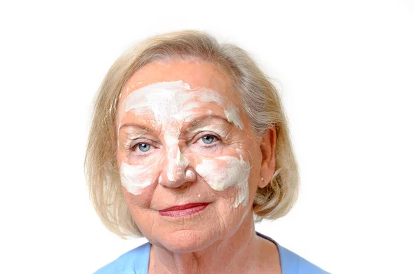 Elderly lady with cosmetic cream on her face — Stock Photo, Image