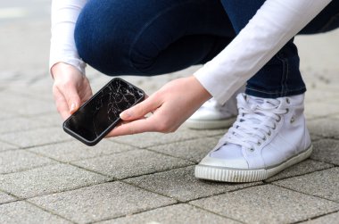 Sokakta kırık telefon alarak diz çöken kişi