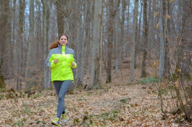 Young woman jogging through winter woodland